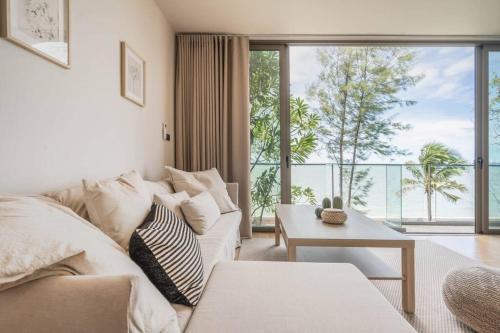 ein Wohnzimmer mit einem weißen Sofa und einem großen Fenster in der Unterkunft Marbella Beachfront Pattaya 3BR in Bang Lamung