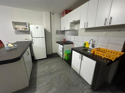 uma pequena cozinha com armários brancos e um lavatório em Departamento en playa San Bartolo - cuarto piso em San Bartolo