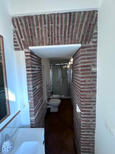 uma casa de banho com uma parede de tijolos e um WC. em La Dimora Dei Papi em Castel Gandolfo