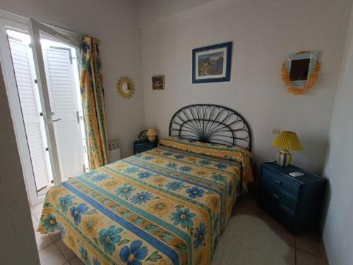 - une chambre avec un lit doté d'un couvre-lit floral et d'une fenêtre dans l'établissement Villa de Charme avec Piscine, Terrasse et VTT, Proche Plage et Commerces - 6 Pers. - FR-1-749-29, au Cap d'Agde