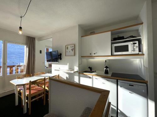 - une cuisine avec une table et un four micro-ondes dans l'établissement Appartement 4 pers avec chambre, casier à skis, balcon, Les Menuires - FR-1-452-387, aux Menuires