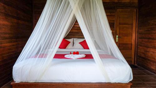 een bed met rode kussens en een witte baldakijn bij D'Lesung Villas Lembongan in Nusa Lembongan