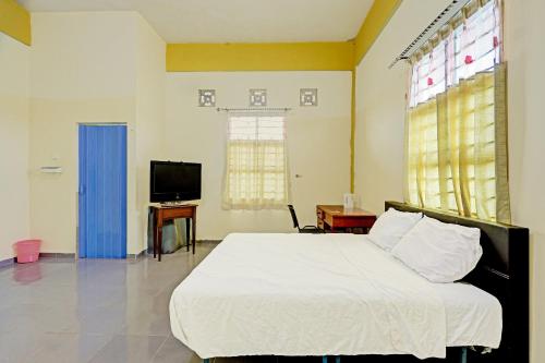 1 dormitorio con 1 cama blanca y TV en Collection O 91499 John Lebron House, en Sagulung