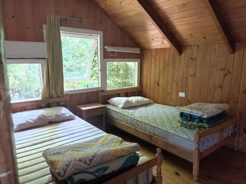 Habitación de madera con 2 camas y 2 ventanas en Gran casa a orillas del lago, en Licán Ray