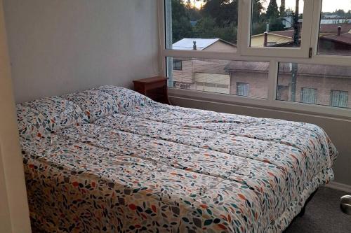 un dormitorio con una cama y una ventana en Departamento central Temuco, en Temuco