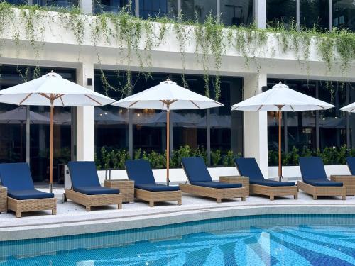 a group of chairs and umbrellas next to a pool at La Green Hotel and Residence in Bang Tao Beach