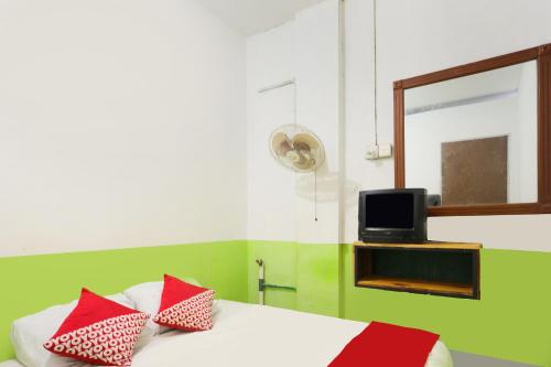 1 dormitorio con 1 cama con almohadas rojas y TV en OYO 91344 Wr House Syariah Batam en Jodoh