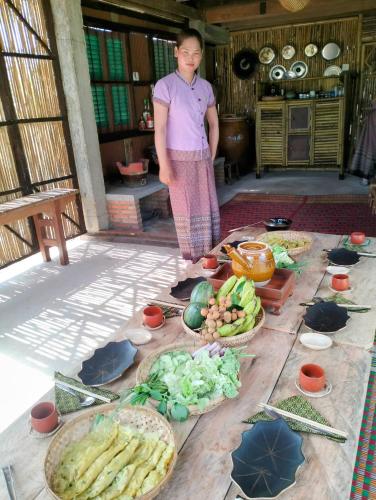 a woman standing in front of a table of food at Banteay Srey Women's Only Traditional Spa and Homestay in Kampot