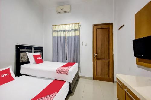 a hotel room with two beds and a television at OYO 92065 Kos Flobamor in Kupang