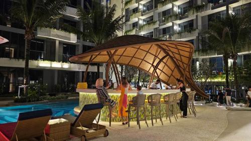 a group of people sitting at a bar under an umbrella at La Green Hotel and Residence in Bang Tao Beach