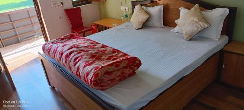 a bed with a red blanket on top of it at Wild House Home stay in Jhirna