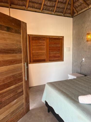 a bedroom with a bed and a wooden door at Pacas Suítes Casa & Chalés in Santo Amaro