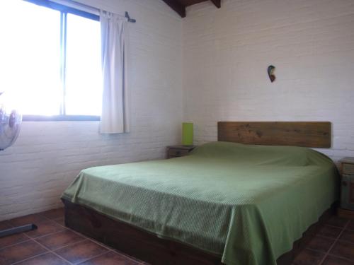 a bedroom with a green bed in a room with a window at Casa 7 Cerros in Piriápolis