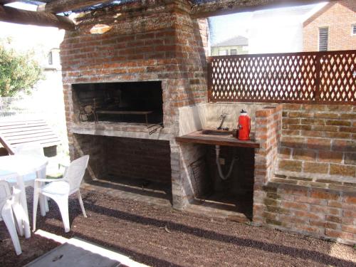 a brick fireplace with a sink and a table on a patio at Casa 7 Cerros in Piriápolis