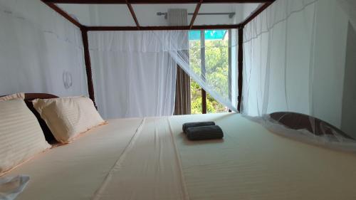 - une chambre avec un lit blanc et une fenêtre dans l'établissement Nirmali Resort, à Mirissa
