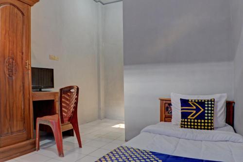 een slaapkamer met een bed, een bureau en een stoel bij SPOT ON 92834 Wisma Dira Tiara Syariah in Lampung