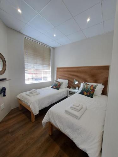 a room with two beds and a window in it at The Stetson in Paarl