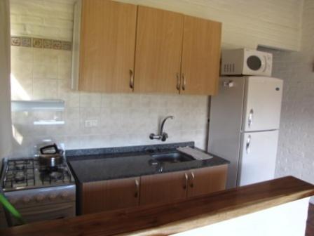 a kitchen with a sink and a stove and a refrigerator at Casa 7 Cerros in Piriápolis