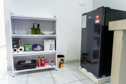 a small refrigerator sitting in a room next to a shelf at Tok Umi Guesthouse@AMJ Bakri in Muar