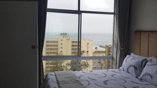a bedroom with a window with a view of the ocean at Oceanic,unit 124 ocean view in Durban