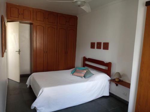 a bedroom with a white bed and wooden cabinets at apartamento fofo Astúrias in Guarujá