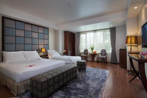 a hotel room with two beds and a table and chairs at Hanoi Dragon Boutique Hotel in Hanoi