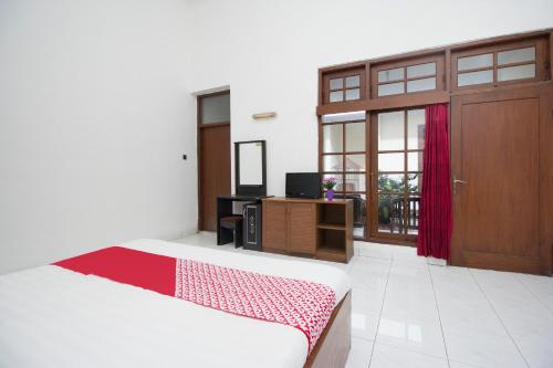 1 dormitorio con cama, puerta y TV en Super OYO 759 Hotel Dewi Sri, en Timuran