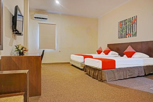 a hotel room with two beds and a television at Collection O 91414 Hotel Marina Beach in Makassar