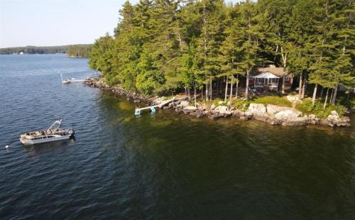 a boat in the water next to a house at PLACYD PINES LIMIT 8 cottage in North Sebago