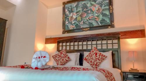 a bedroom with a large bed with red and white pillows at Villa Cendrawasih Ubud in Tegalalang