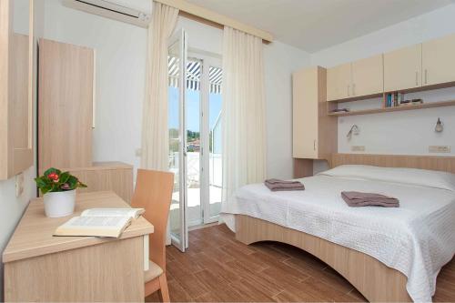 Dormitorio con cama y escritorio con libro en Guest House Lovrić, en Lumbarda