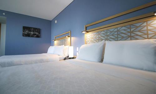 a bedroom with two beds and a blue wall at Holiday Inn Express Mexico Reforma by IHG in Mexico City