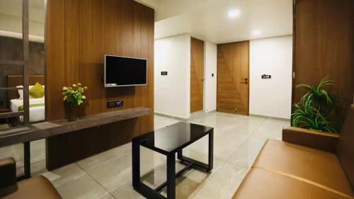 Hotel R City Inn By Mantram Hospitality في راجكوت: غرفة معيشة مع طاولة وتلفزيون