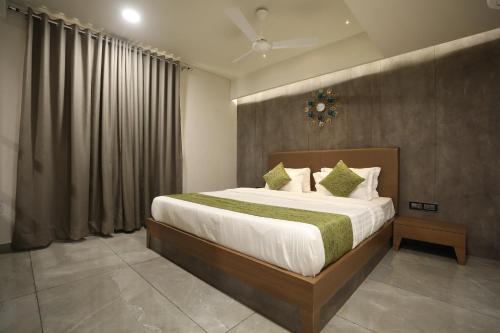 Hotel R City Inn By Mantram Hospitality في راجكوت: غرفة نوم بسرير كبير ومخدات خضراء