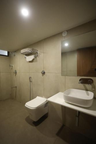 a bathroom with a white toilet and a sink at Hotel R City Inn By Mantram Hospitality in Rajkot