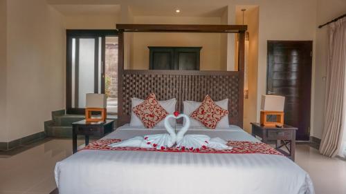a bedroom with a large white bed with a towel on it at Villa Cendrawasih Ubud in Tegalalang