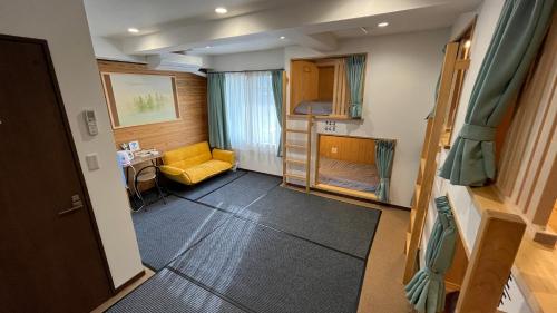 een kleine kamer met een gele stoel en een bureau bij オレンジの風 in Imabari