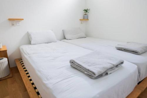 two beds in a room with white sheets and towels at 葉山 森戸海岸すぐの富士山と海が一望できる新築ヴィラ bbq サウナ in Hayama
