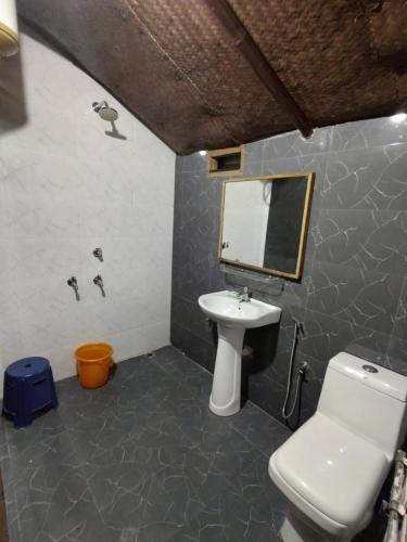 a bathroom with a sink and a toilet and a mirror at AVA Resort, Kaziranga in Bokakhat