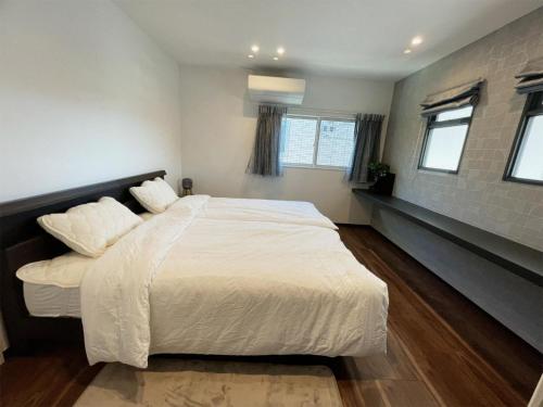 1 dormitorio con 1 cama blanca grande y ventanas en 熊本民宿-悠然别苑, en Ozu