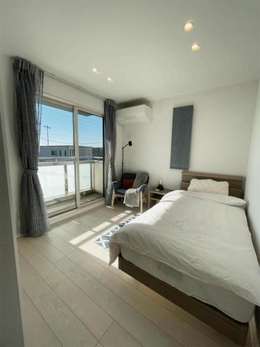 1 dormitorio con cama y ventana grande en 熊本民宿-悠然别苑, en Ozu