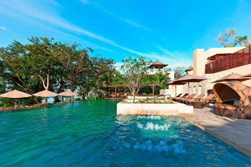 einen Pool in einem Resort mit Tischen und Sonnenschirmen in der Unterkunft The Westin Siray Bay Resort & Spa, Phuket in Phuket