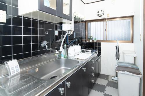 a kitchen with a stainless steel sink and black tiles at リノディア京橋 in Osaka