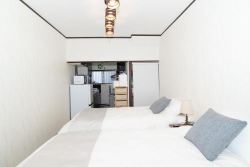 a white bedroom with two beds and a lamp at リノディア京橋 in Osaka