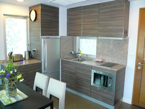 a kitchen with wooden cabinets and a table with chairs at Baan San Dao Hua Hin in Hua Hin