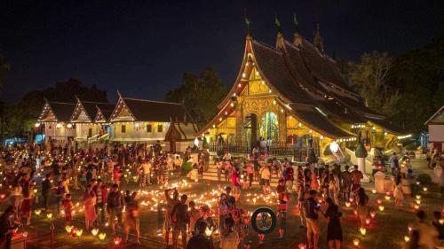 una multitud de personas de pie en frente de un edificio con luces en Villa Phathana Royal View Hotel en Luang Prabang