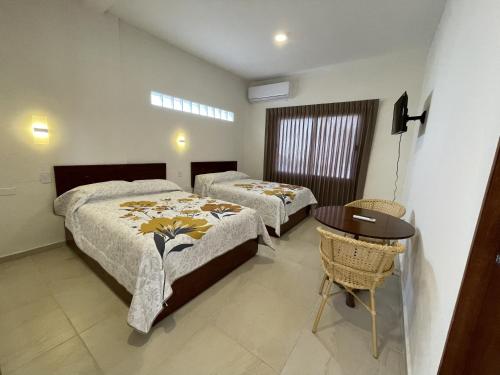 1 dormitorio con 2 camas y mesa. en Hotel Allende, en La Paz