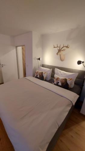 a large white bed with pillows and a deer head on the wall at Ferienwohnung Bergblume in Bolsterlang