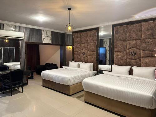 a hotel room with two beds and a desk at Hotel Oasis by Signature in Islamabad
