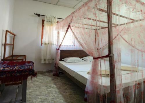 a bedroom with a bed with a mosquito net at Kancia in Mirissa